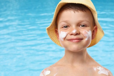 Image of Little boy with sun protection product on his skin by outdoor swimming pool