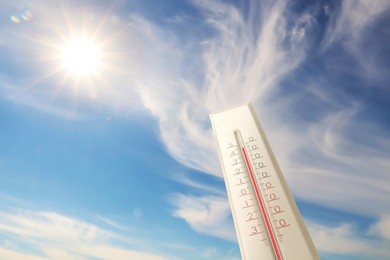 Image of Extremely high temperature on thermometer against blue sky on sunny day. Summer weather