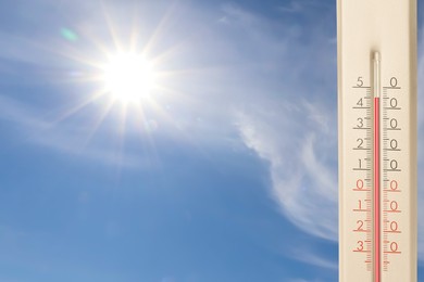 Image of Extremely high temperature on thermometer against blue sky on sunny day. Summer weather