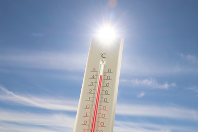 Image of Extremely high temperature on thermometer against blue sky on sunny day. Summer weather