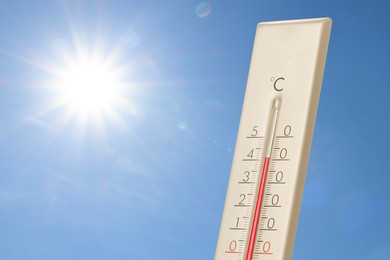 Image of High temperature on thermometer against blue sky on sunny day. Summer weather