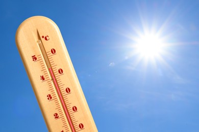 Image of Extremely high temperature on thermometer against blue sky on sunny day. Summer weather