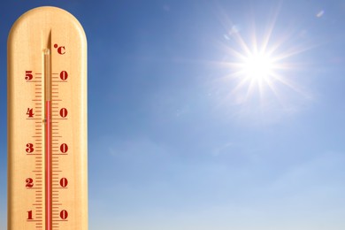 Image of Extremely high temperature on thermometer against blue sky on sunny day. Summer weather