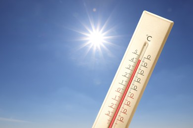 Image of Extremely high temperature on thermometer against blue sky on sunny day. Summer weather