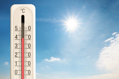 Image of High temperature on thermometer against blue sky on sunny day. Summer weather