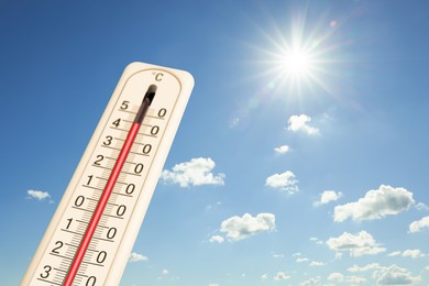 Image of Extremely high temperature on thermometer against blue sky on sunny day. Summer weather