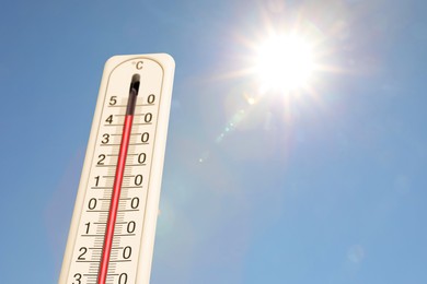 Image of Extremely high temperature on thermometer against blue sky on sunny day. Summer weather