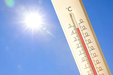 Image of Extremely high temperature on thermometer against blue sky on sunny day. Summer weather