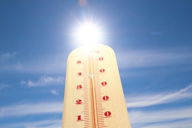 Image of High temperature on thermometer against blue sky on sunny day. Summer weather