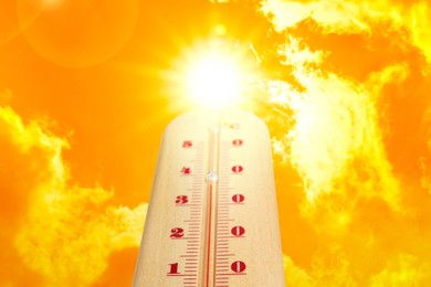 Image of High temperature on thermometer against orange sky on sunny day. Hot summer weather