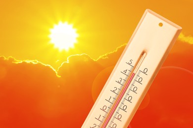 Image of Extremely high temperature on thermometer against orange sky on sunny day. Severely hot summer weather