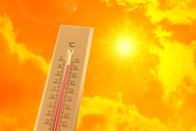 Image of Extremely high temperature on thermometer against orange sky on sunny day. Severely hot summer weather