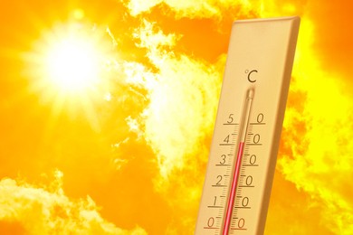 Image of High temperature on thermometer against orange sky on sunny day. Hot summer weather