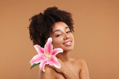 Photo of Portrait of beautiful Brazilian woman with lily flower after spa treatment on light brown background