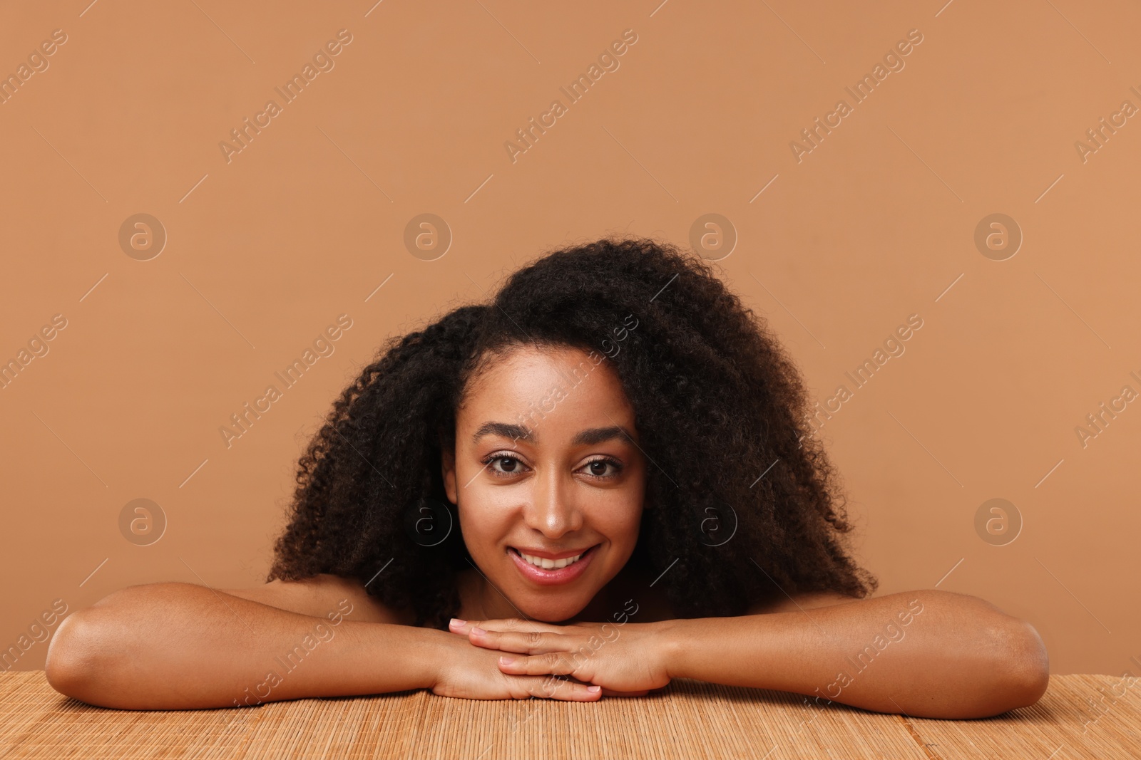 Photo of Portrait of beautiful Brazilian woman after spa treatment at bamboo table on beige background