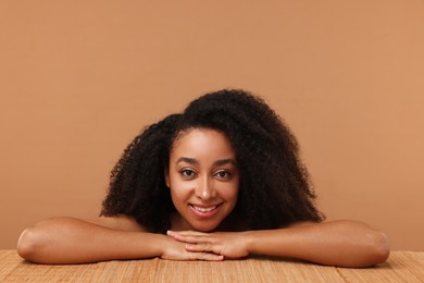 Photo of Portrait of beautiful Brazilian woman after spa treatment at bamboo table on beige background