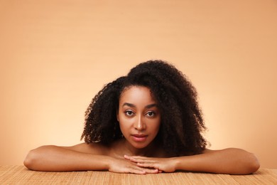 Photo of Portrait of beautiful Brazilian woman after spa treatment at bamboo table on beige gradient background