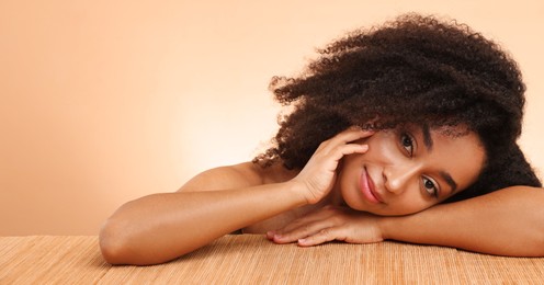 Photo of Portrait of beautiful Brazilian woman after spa treatment at bamboo table on beige gradient background