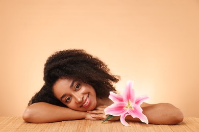 Photo of Portrait of beautiful Brazilian woman with lily flower after spa treatment at bamboo table on beige gradient background