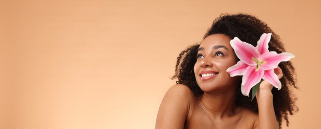 Photo of Portrait of beautiful Brazilian woman with lily flower after spa treatment on beige gradient background. Space for text