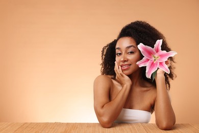 Photo of Portrait of beautiful Brazilian woman with lily flower after spa treatment at bamboo table on beige gradient background. Space for text