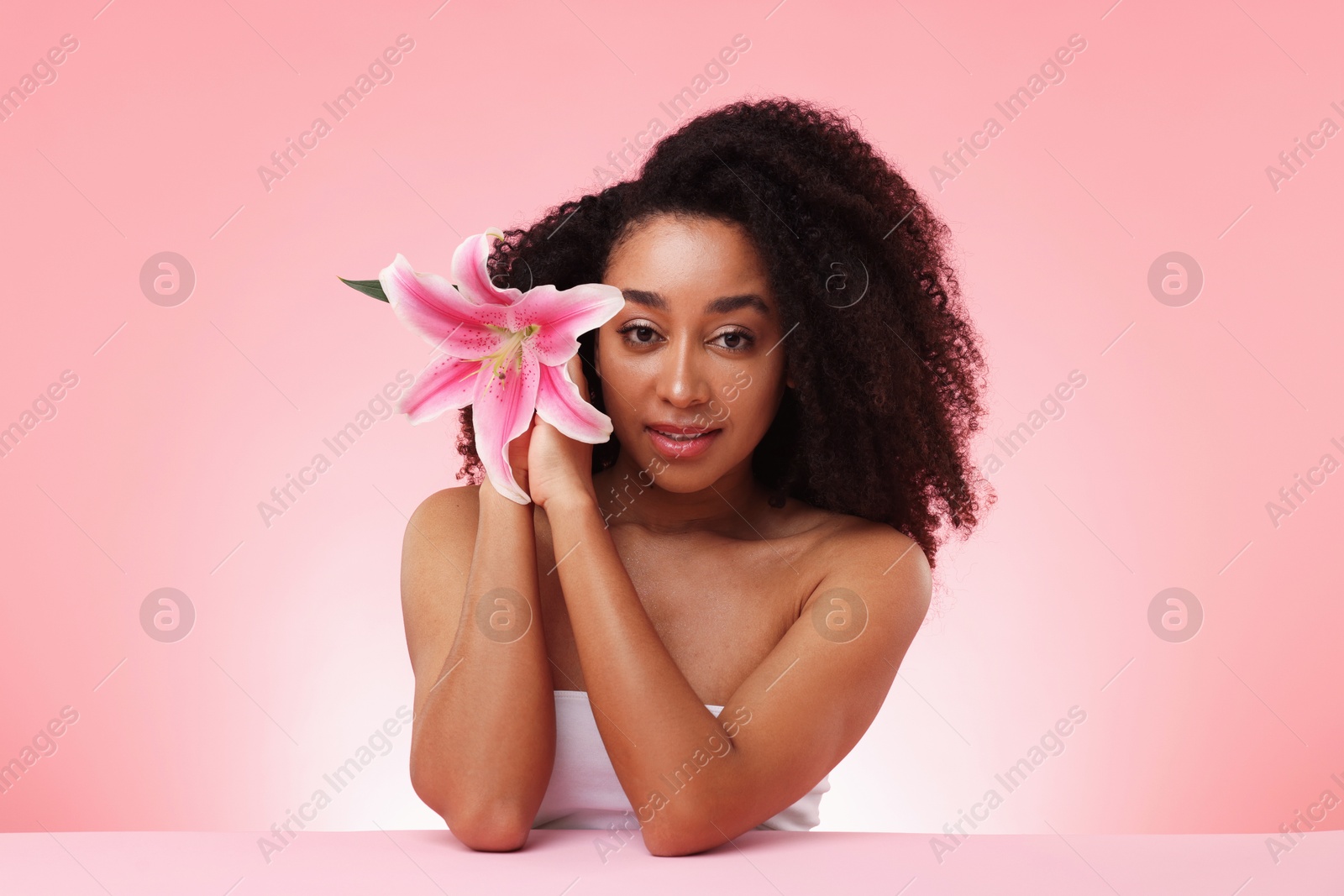 Photo of Portrait of beautiful Brazilian woman with lily flower after spa treatment on pink gradient background