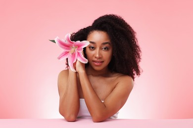 Photo of Portrait of beautiful Brazilian woman with lily flower after spa treatment on pink gradient background