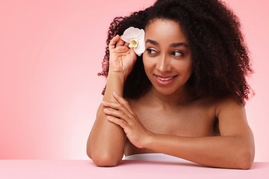 Photo of Portrait of beautiful Brazilian woman with orchid flower after spa treatment on pink gradient background
