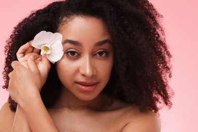 Photo of Portrait of beautiful Brazilian woman with orchid flower after spa treatment on pink background, closeup