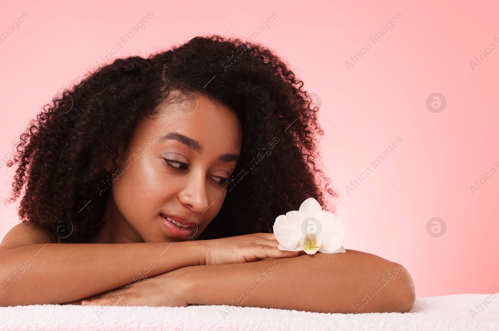Portrait of beautiful Brazilian woman with orchid flower after spa treatment on pink gradient background Photo of Portrait of beautiful Brazilian woman with orchid flower after spa treatment on pink gradient background