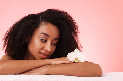 Photo of Portrait of beautiful Brazilian woman with orchid flower after spa treatment on pink gradient background