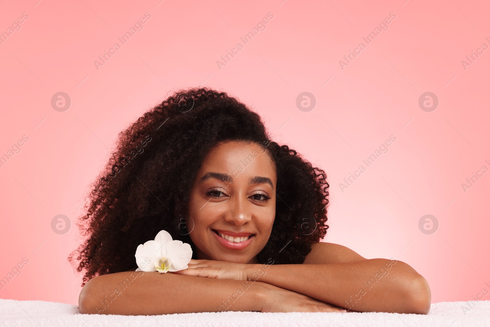 Portrait of beautiful Brazilian woman with orchid flower after spa treatment on pink gradient background Photo of Portrait of beautiful Brazilian woman with orchid flower after spa treatment on pink gradient background