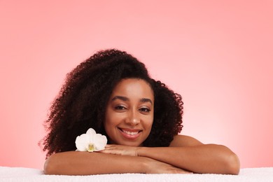 Photo of Portrait of beautiful Brazilian woman with orchid flower after spa treatment on pink gradient background
