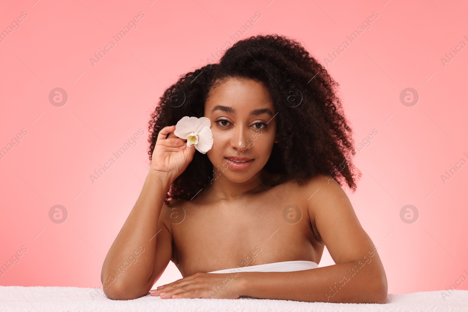 Portrait of beautiful Brazilian woman with orchid flower after spa treatment on pink gradient background Photo of Portrait of beautiful Brazilian woman with orchid flower after spa treatment on pink gradient background