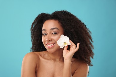 Photo of Portrait of beautiful Brazilian woman with orchid flower after spa treatment on light blue background