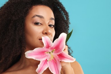 Photo of Portrait of beautiful Brazilian woman with lily flower after spa treatment on light blue background, closeup