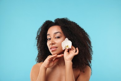 Photo of Portrait of beautiful Brazilian woman with orchid flower after spa treatment on light blue background