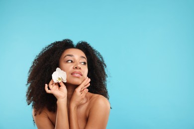 Photo of Portrait of beautiful Brazilian woman with orchid flower after spa treatment on light blue background. Space for text