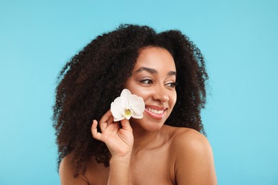 Photo of Portrait of beautiful Brazilian woman with orchid flower after spa treatment on light blue background