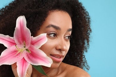 Photo of Portrait of beautiful Brazilian woman with lily flower after spa treatment on light blue background, closeup