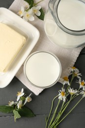 Photo of Fresh dairy products and flowers on grey wooden table, flat lay