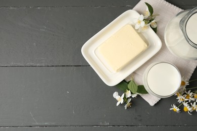 Photo of Fresh dairy products and flowers on grey wooden table, flat lay. Space for text