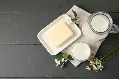 Photo of Fresh dairy products and flowers on grey wooden table, flat lay. Space for text