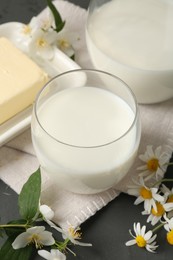 Photo of Fresh dairy products and flowers on grey wooden table, closeup
