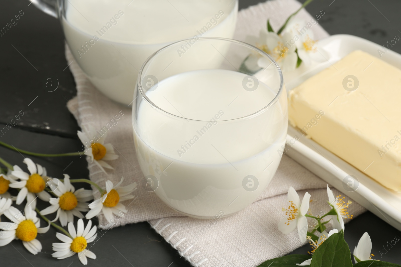 Photo of Fresh dairy products and flowers on grey wooden table, closeup
