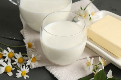 Photo of Fresh dairy products and flowers on grey wooden table, closeup
