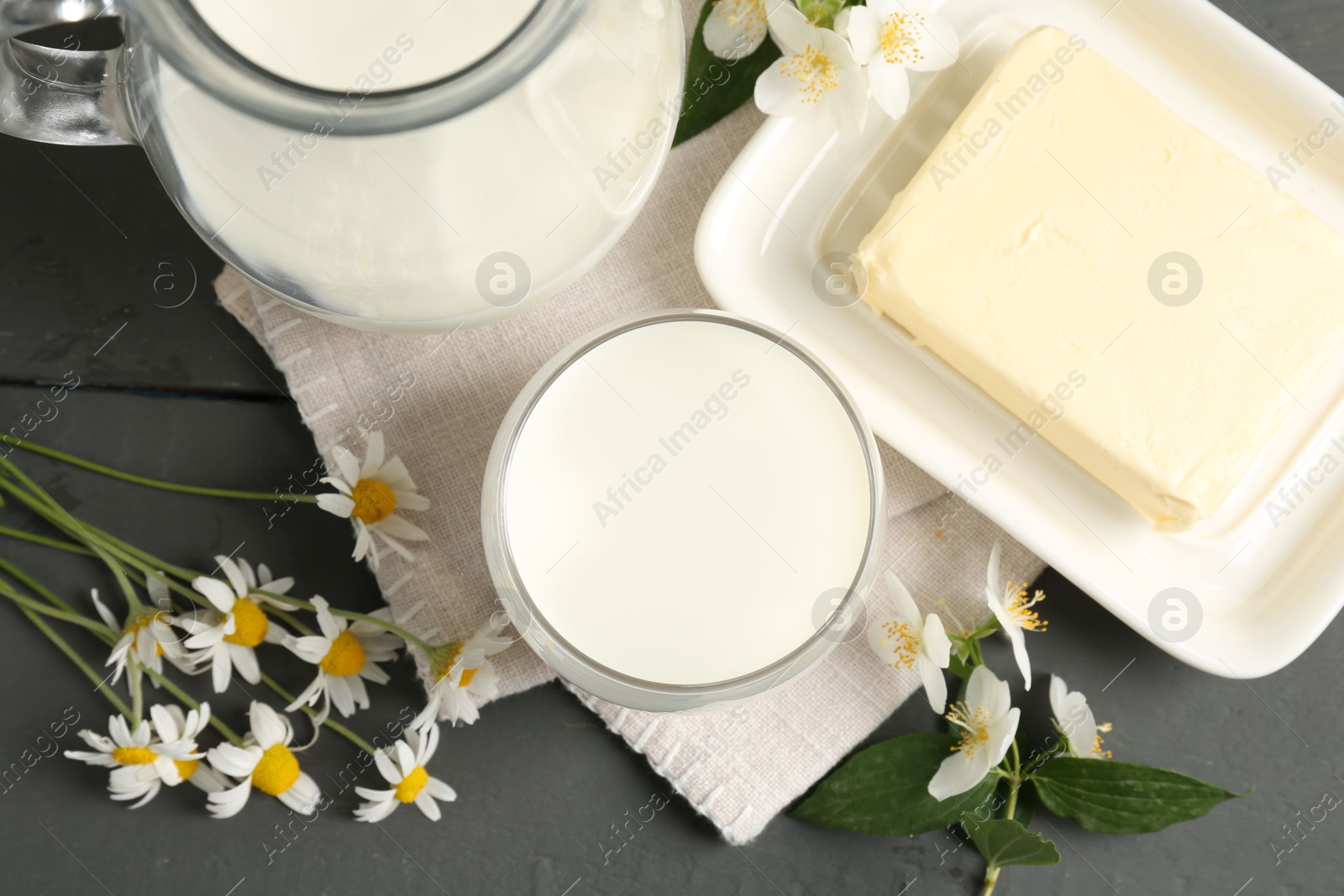 Photo of Fresh dairy products and flowers on grey wooden table, flat lay