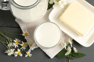 Photo of Fresh dairy products and flowers on grey wooden table, flat lay