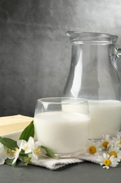 Photo of Fresh dairy products and flowers on grey wooden table against textured background, closeup