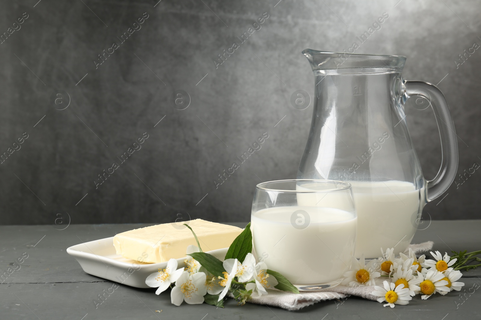 Fresh dairy products and flowers on grey wooden table against textured background. Space for text Photo of Fresh dairy products and flowers on grey wooden table against textured background. Space for text